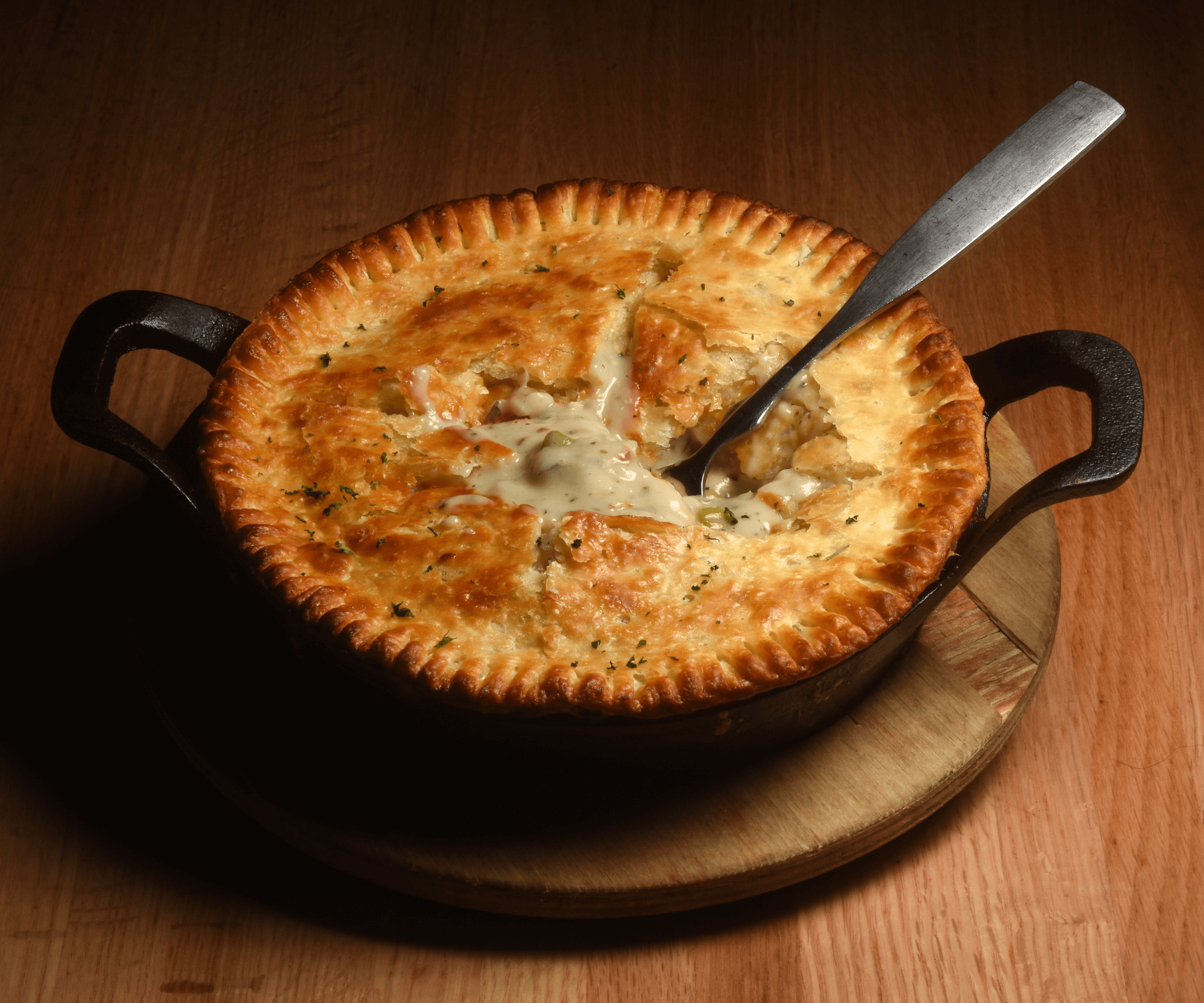 Chicken pot pie in cast iron pan with serving spoon in it.